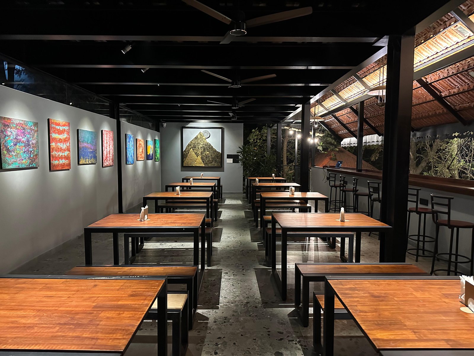 Inside Day One — long wooden tables under a thatched ceiling, art on the walls