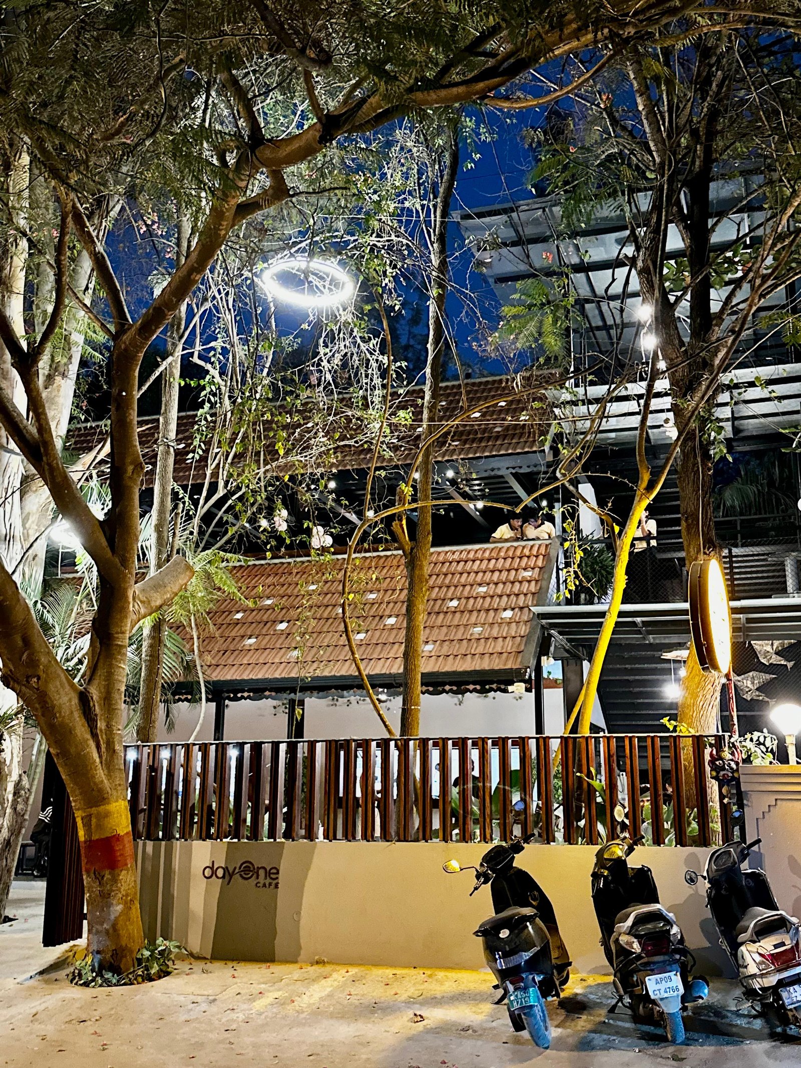 Day One Cafe exterior — terracotta roof and fairy lights through the trees at night